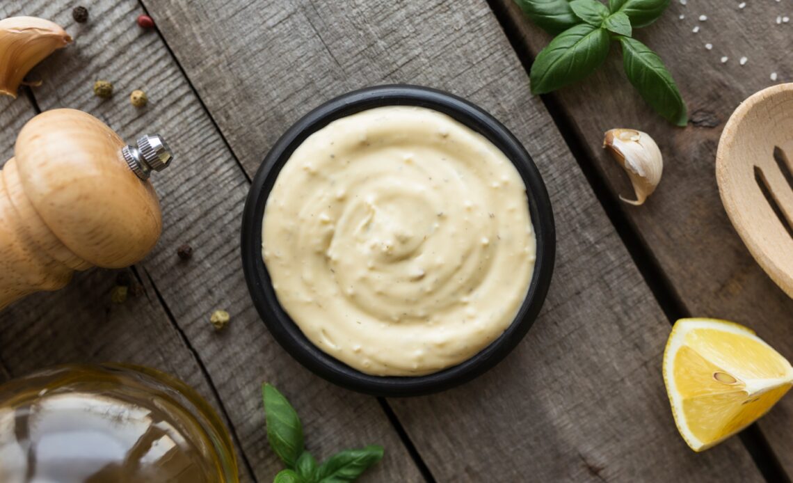 Cooking homemade mayonnaise, garlic cream sauce. Seasonings on wooden background