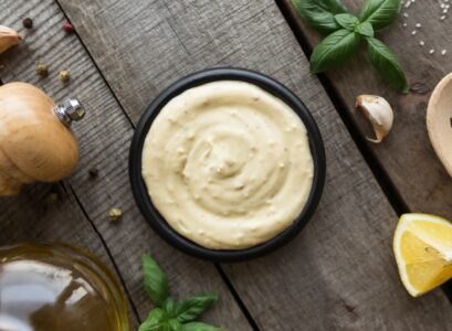 Cooking homemade mayonnaise, garlic cream sauce. Seasonings on wooden background